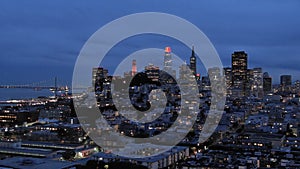 footage of skyscrapers and office buildings in the city skyline and the San Francisco Oakland Bay Bridge at night with lights