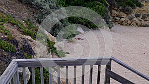 Footage of someone walking down wooden stairs leading to a beach known as Praia da Oura beach in Albufeira in Portugal on a hot