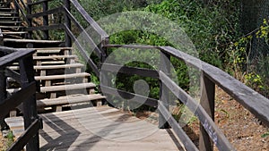 Footage of someone walking up wooden stairs leading from a beach known as Praia da Oura beach in Albufeira in Portugal on a hot