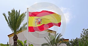 Footage of a Spanish flag blowing in the wind on a bright sunny summers day with blue skys, taken in the town of Benidorm in Spain