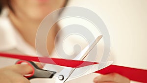 Footage of a woman cutting the red tape celebrating the opening or beginning of something