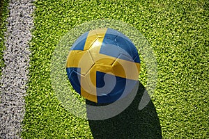 football ball with the flag of sweden on the green field near the white line