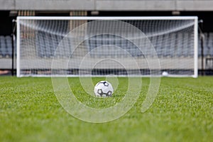 Football ball on fresh green grass pitch. Soccer ball at big stadium