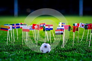 Football ball on green grass and all national flags of World Cup in Russia 2018