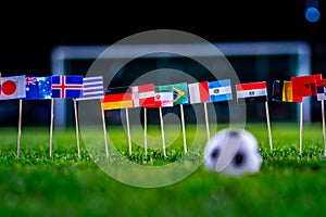 Football ball on green grass and all national flags of World Cup in Russia 2018