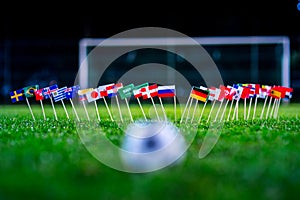 Football ball on green grass and all national flags of World Cup in Russia 2018