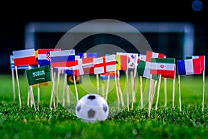 Football ball on green grass and all national flags of World Cup in Russia 2018