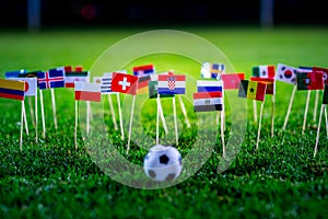 Football ball on green grass and all national flags of World Cup in Russia 2018