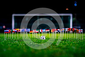 Football ball on green grass and all national flags of World Cup in Russia 2018