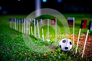 Football ball on green grass and all national flags of World Cup in Russia 2018