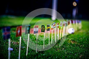 Football ball on green grass and all national flags of World Cup in Russia 2018