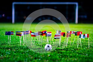 Football ball on green grass and all national flags of World Cup in Russia 2018