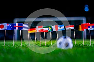 Football ball on green grass and all national flags of World Cup in Russia 2018