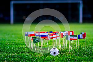 Football ball on green grass and all national flags of World Cup in Russia 2018