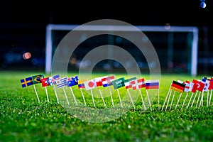 Football ball on green grass and all national flags of World Cup in Russia 2018