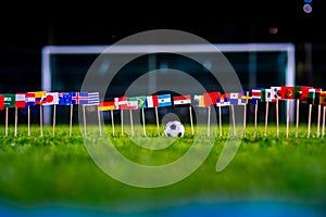 Football ball on green grass and all national flags of World Cup in Russia 2018