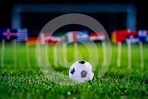 Football ball on green grass and all national flags of World Cup in Russia 2018