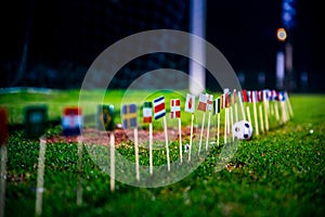 Football ball on green grass and all national flags of World Cup in Russia 2018