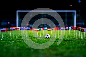 Football ball on green grass and all national flags of World Cup in Russia 2018