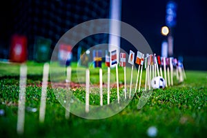 Football ball on green grass and all national flags of World Cup in Russia 2018