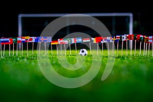 Football ball on green grass and all national flags of World Cup in Russia 2018