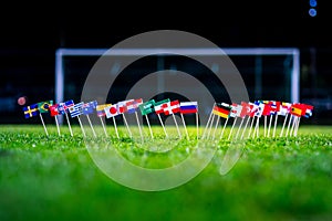 Football ball on green grass and all national flags of World Cup in Russia 2018