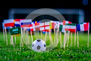 Football ball on green grass and all national flags of World Cup in Russia 2018