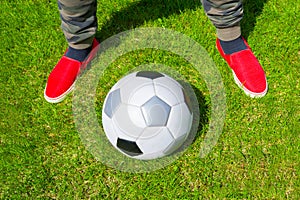 A football ball and legs, a close-up in the grass on a sunny day. A football field. A view from above