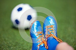 Football boots of boy soccer player with ball on green