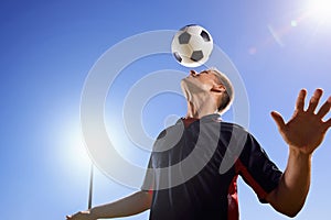 Football, bounce and head with man, game and training with competition, sunshine and exercise. Blue sky, lens flare and