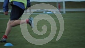 Football club training. A close-up of the player`s legs jumping over the barrier and running across the field. Slow