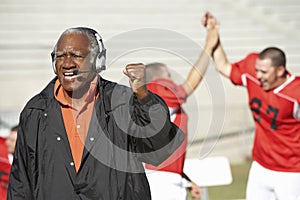 Football Coach Pumping With Players In Background