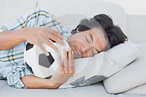 Football fan hugging ball on couch