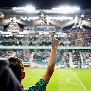 Football fan with raised hands at the stadium during his favorite team match. photo
