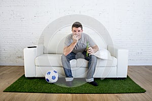 Football fan watching tv match on sofa with grass pitch carpet i