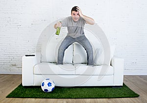 Football fan watching tv match on sofa with grass pitch carpet in stress