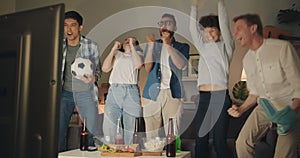 Football fans watching game on TV at home celebrating victory at night