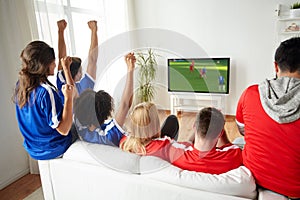 Football fans watching soccer game on tv at home