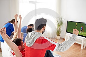 Football fans watching soccer game on tv at home