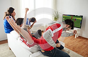 Football fans watching soccer game on tv at home