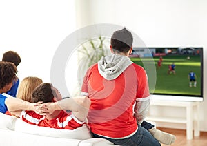 Football fans watching soccer game on tv at home