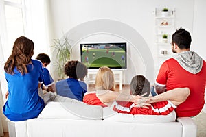 Football fans watching soccer game on tv at home