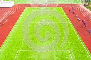 Football field with artificial turf and red running tracks, aerial view