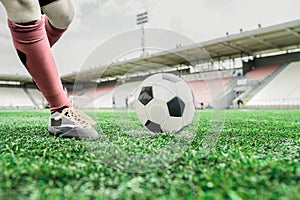 On a football field, a player kicks the ball with his left foot.