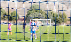 Football game in arena through soccer nets. Blurred background