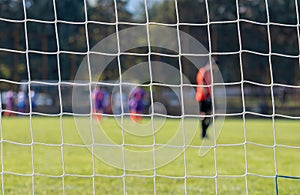 Football game in arena through soccer nets. Blurred background