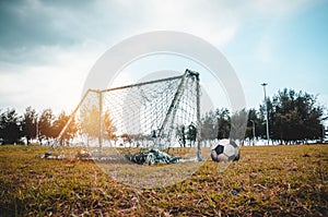 Football gate or soccer goal in neglected on field with football