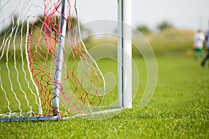 Football goal detail with a soccer players in the background. Football soccer pitch.