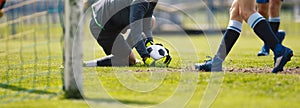 Football Goalkeeper on Knees in Action Catching Ball. Goalie Saving Goal