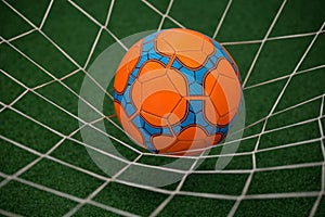 Football in goalpost against artificial grass